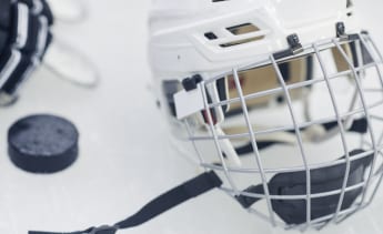Hockey helmet and puck sitting on ice.