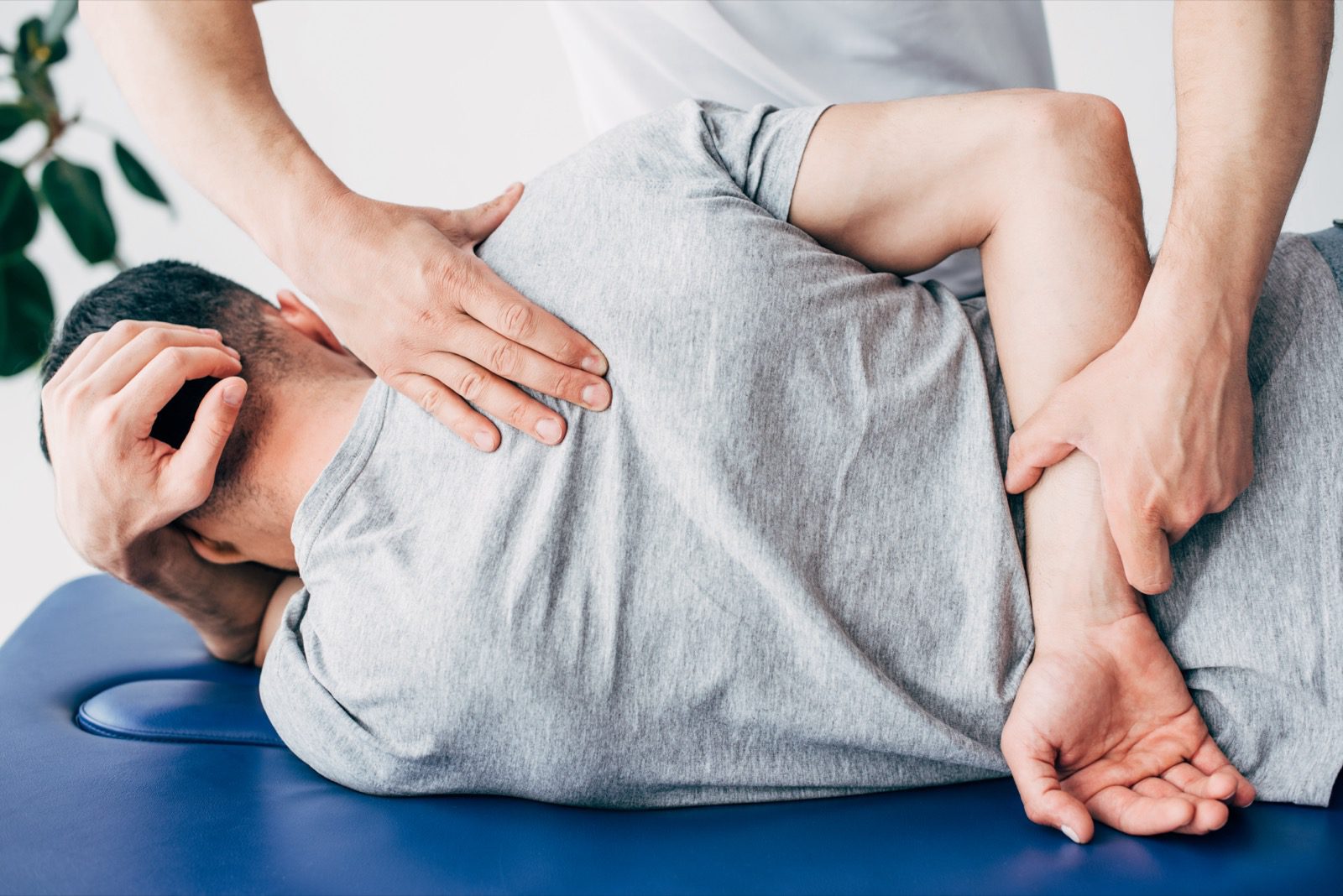 Back view of chiropractor massaging back of man lying on Massage Table