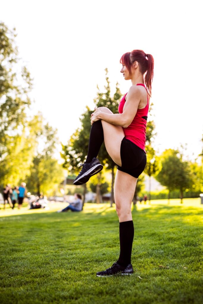 Woman stretching in a park while wearing compression socks
